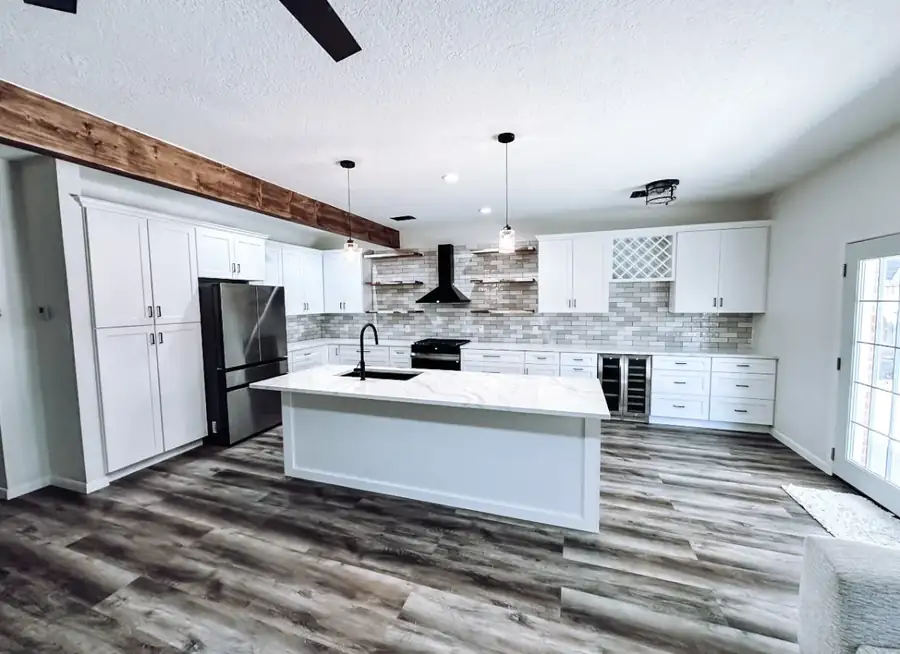 Remodeled custom kitchen with white shaker cabinets, a quartz waterfall island, and a matte-black range hood