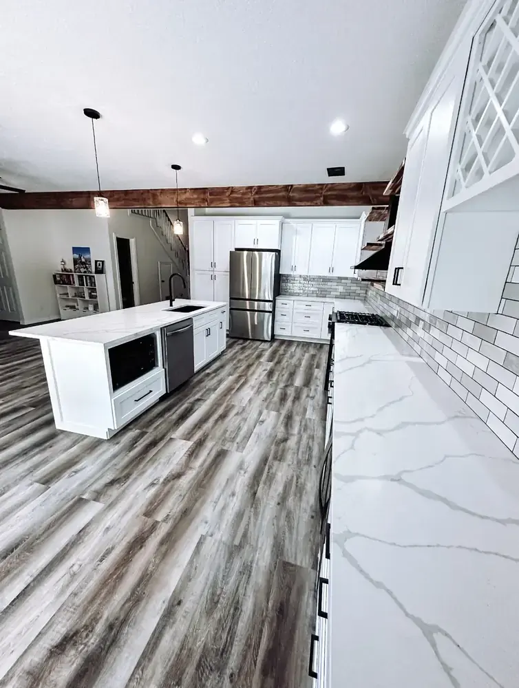 Custom kitchen remodel with white shaker cabinets, calacatta quartz island, wood ceiling beam, pendant lighting, and wine rack cabinet