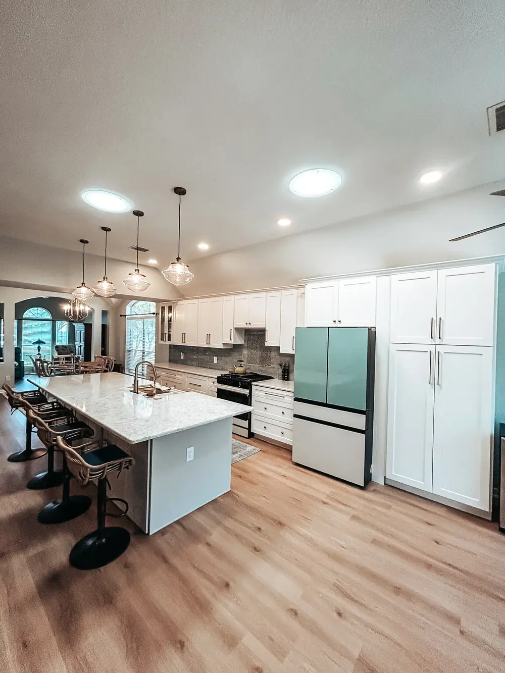 Custom kitchen with white shaker cabinets, gold hardware, and a waterfall quartz island